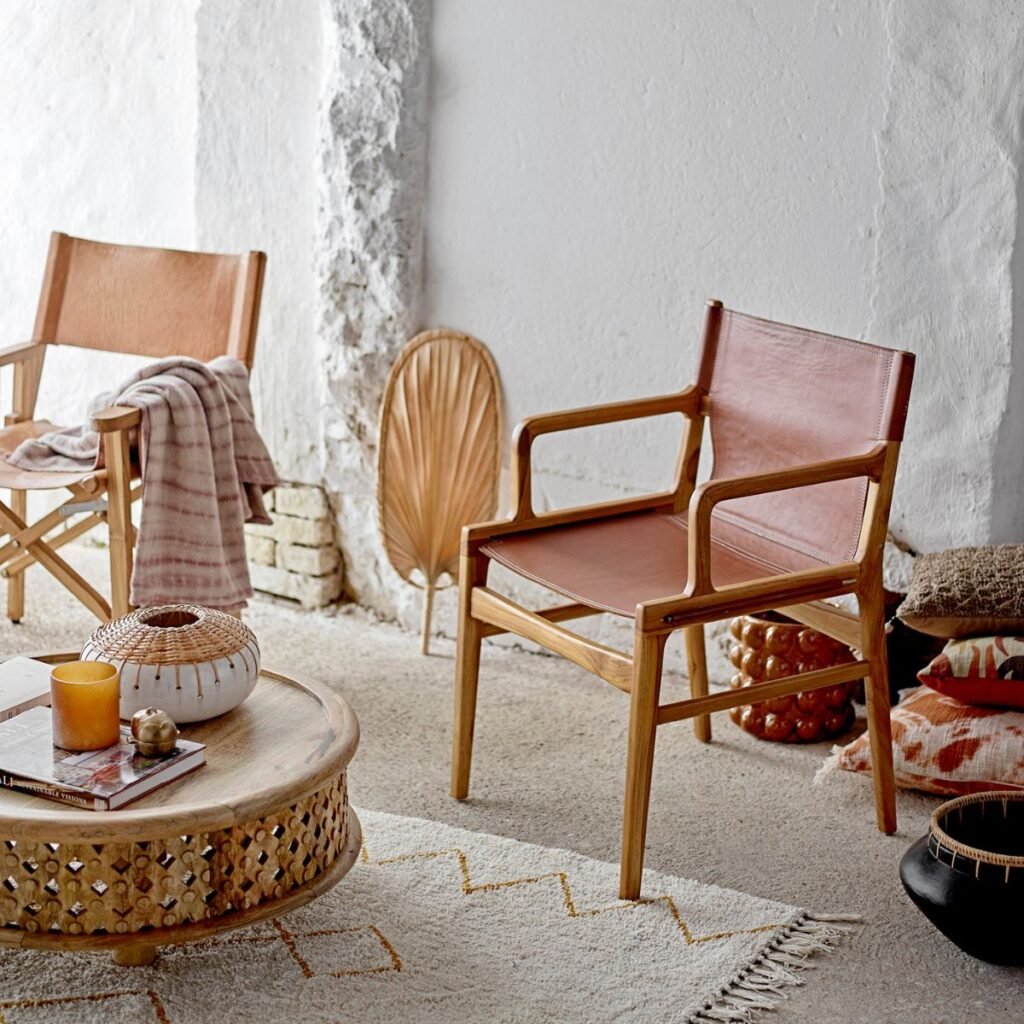 Espace de détente avec deux chaises en cuir marron et bois, accompagnées d’une table basse en bois sculpté et d’éléments décoratifs naturels.